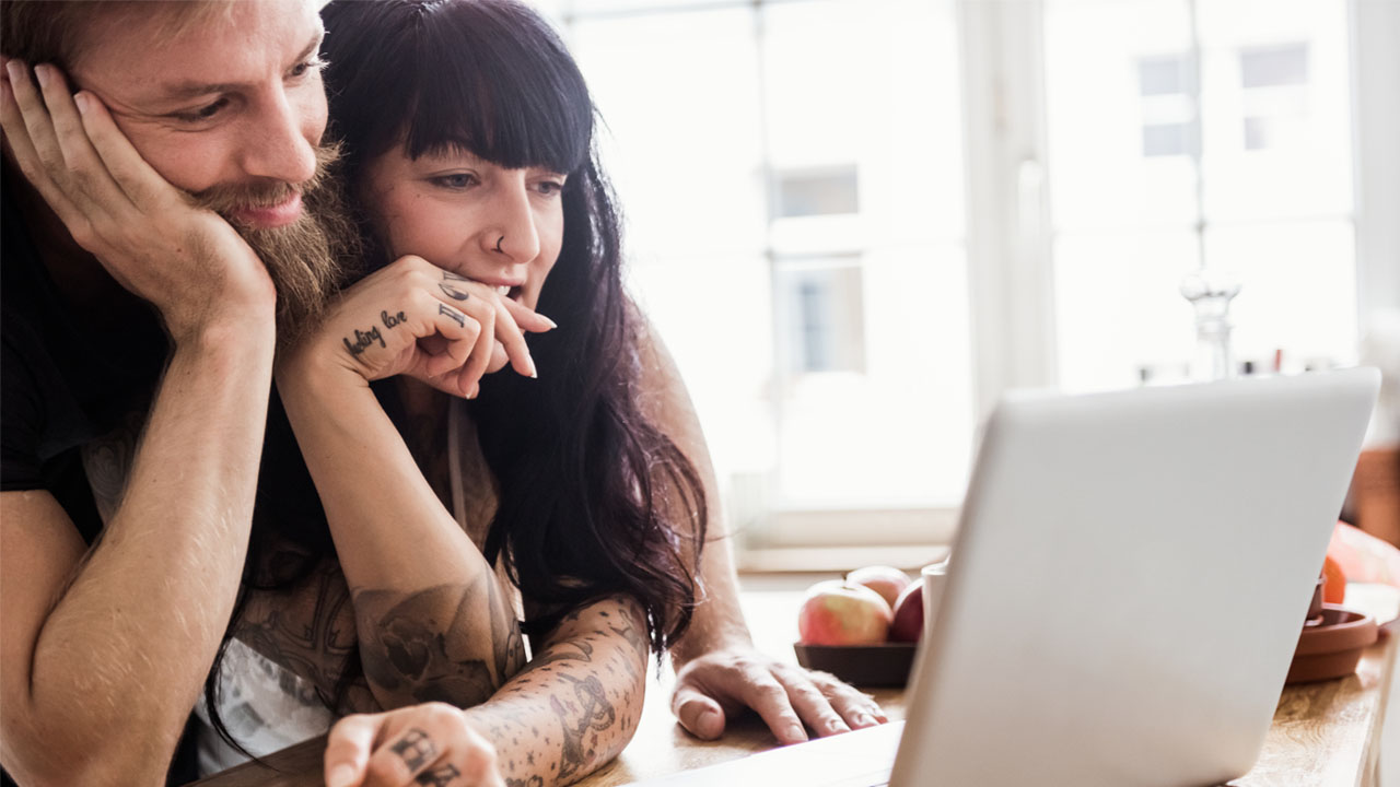 A man and woman focused on a laptop screen