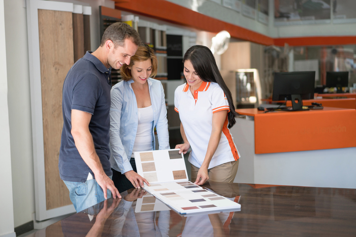 Couple at a floor store looking at wood samples and talking to saleswoman