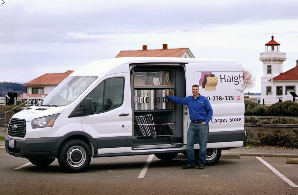 Mobile Carpet Store service van from Haight Carpet & Interiors, with an employee standing beside an open display of flooring samples.